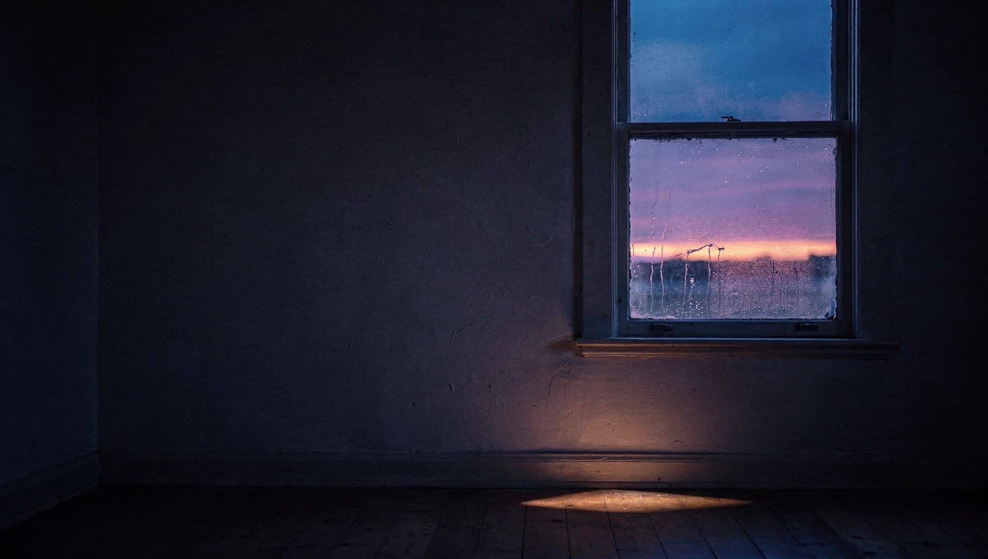 A bare room in cold indigo darkness at civil twilight, its window beaded with condensation framing the violet and ember bands of the pre-dawn sky.